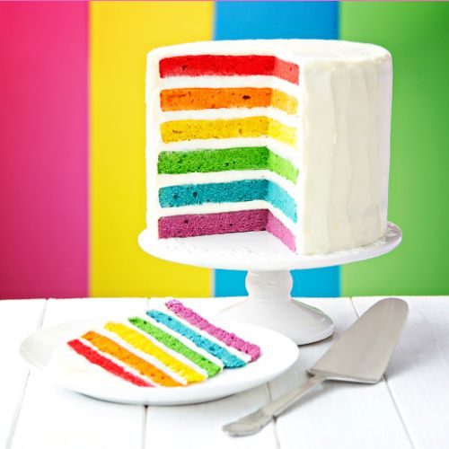 Rainbow layer cake a rainbow layer cake with a slice cut out showing the rainbow coloured layers inside the white frosting